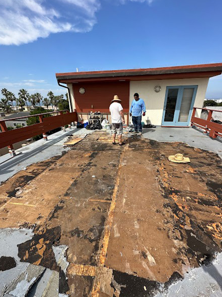 Three construction workers applying bright light blue waterproof coating on outdoor planter